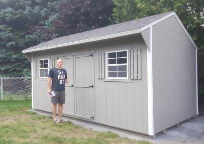 Man standing in front of his new shed giving a thumbs up