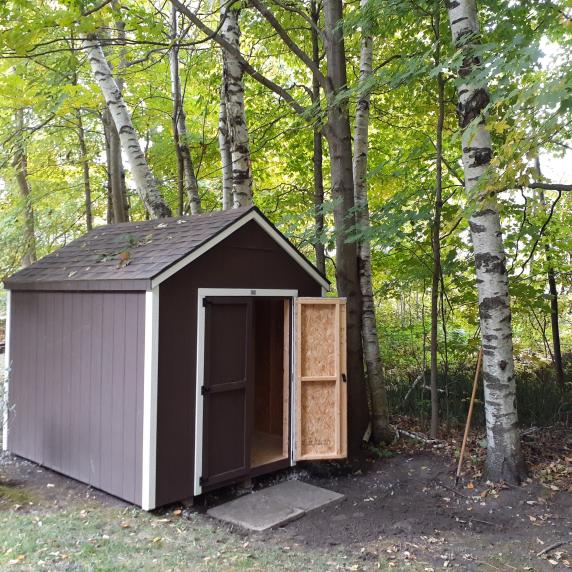 Cottage storage shed open door in the woods
